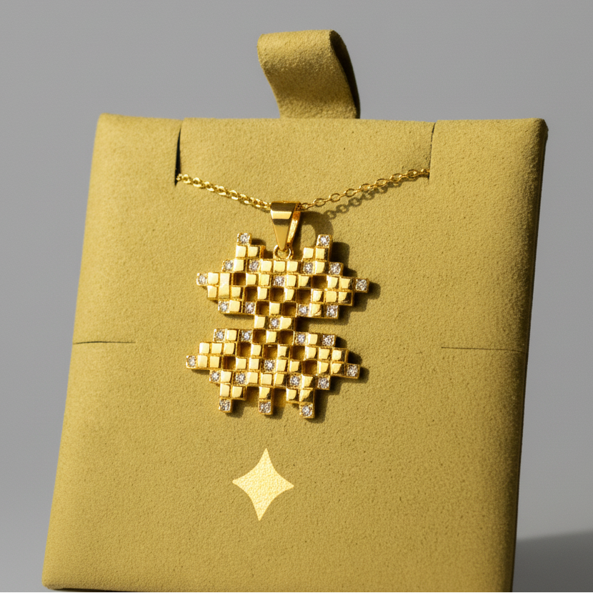 Gold necklace with a geometric design on a gold box against a dark background